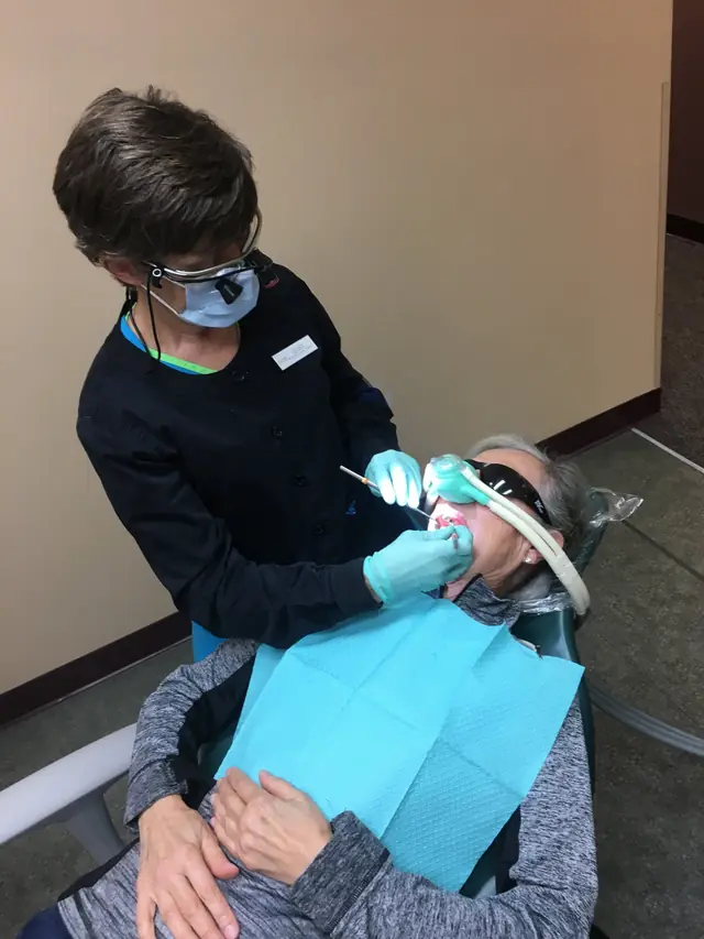 Celeste, a Registered Dental Hygienist at Family Dental Center, treating a seated patient