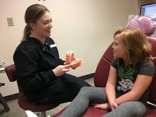 A member of the Family Dental Center staff showing a model of teeth to a young patient