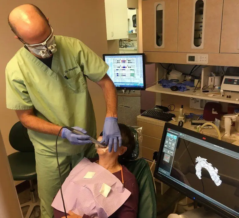 Dr. Weymouth using a digital impression scanner on a patient, with the 3D scan visible on the monitor behind him